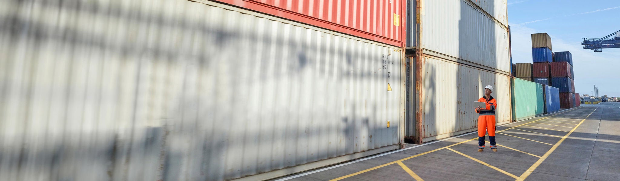 Dock worker with digital tablet inspecting containers