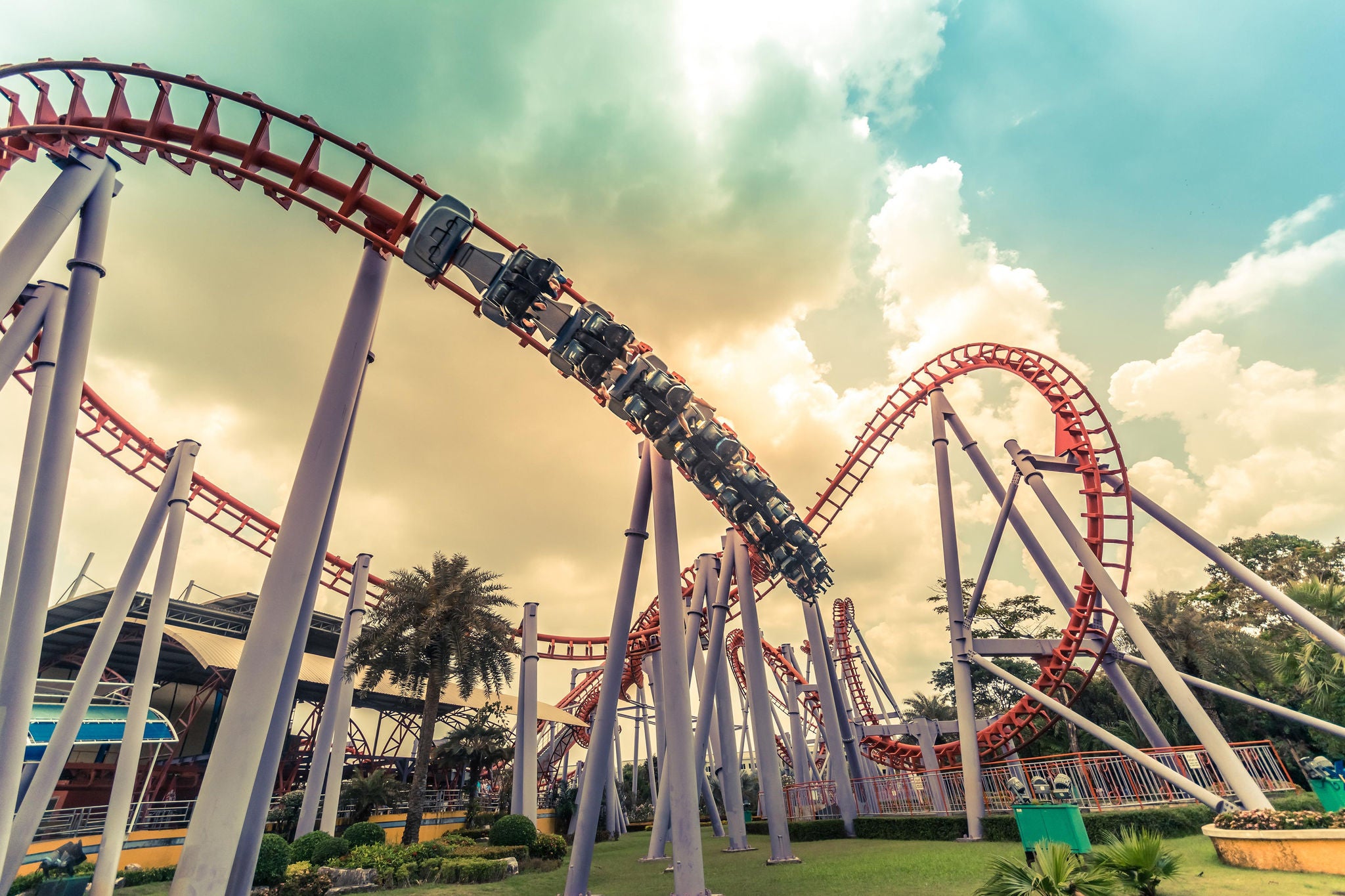 People having fun in a red and circling roller coaster in a sunny day