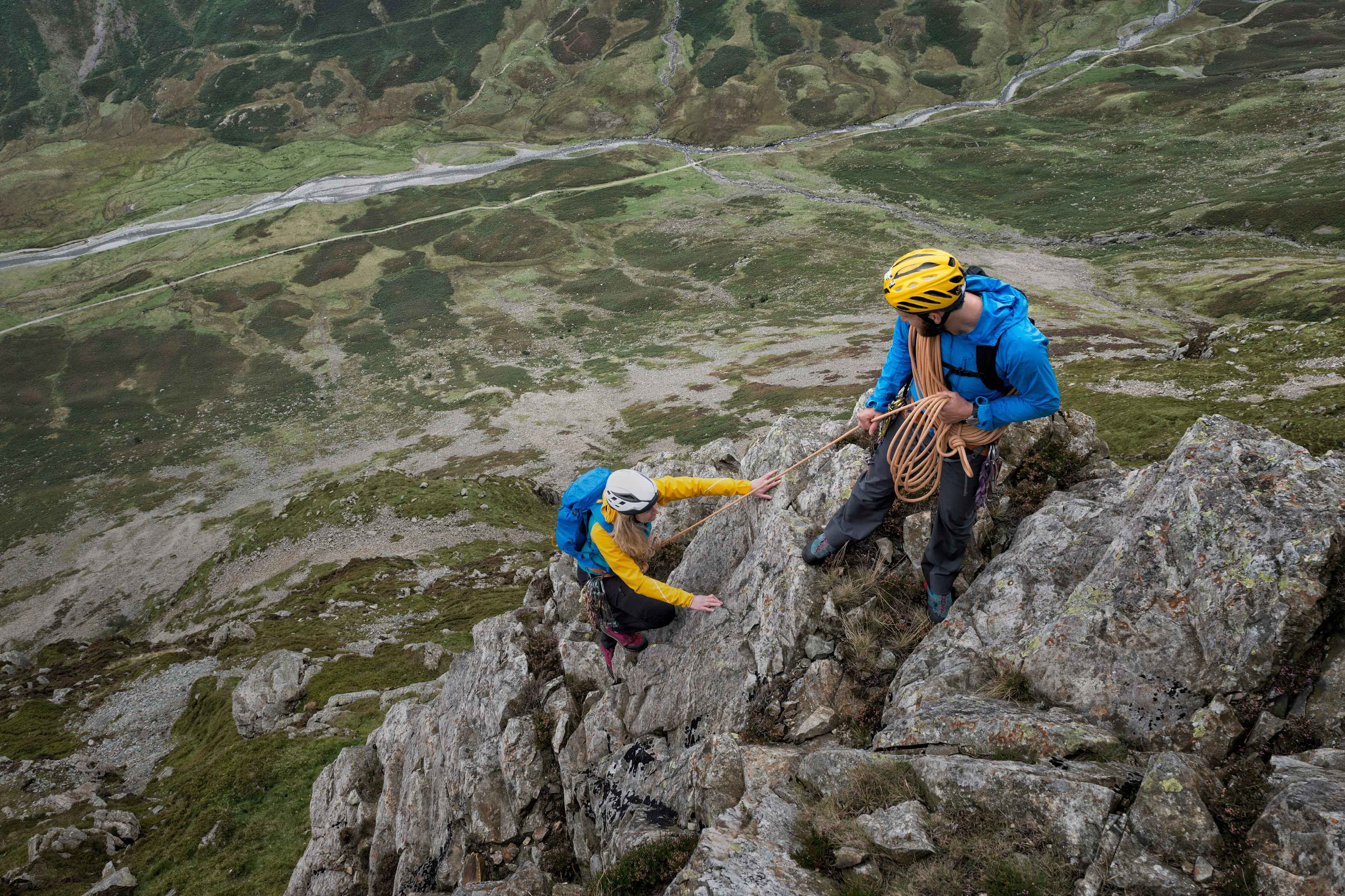 Hiker Woman helping her friend reach the top of the mountain