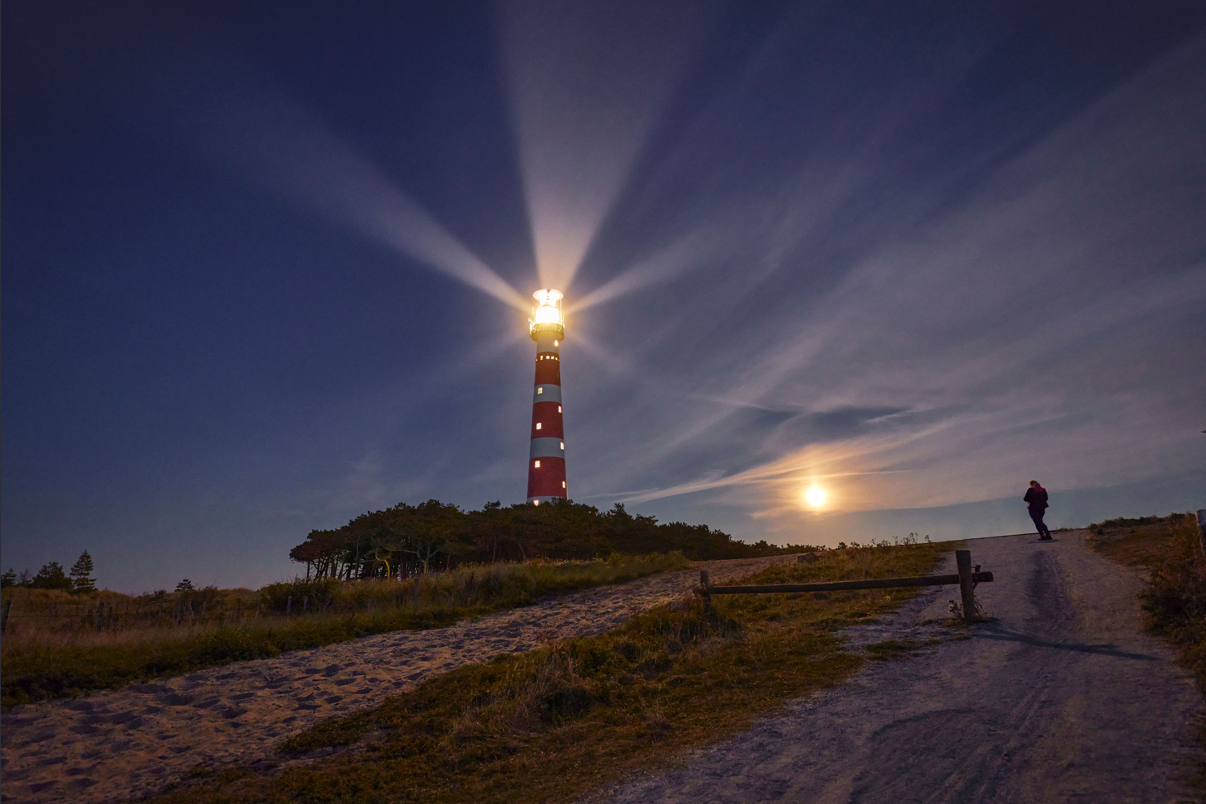 The lighthouse is red and white colored and shines brightly.