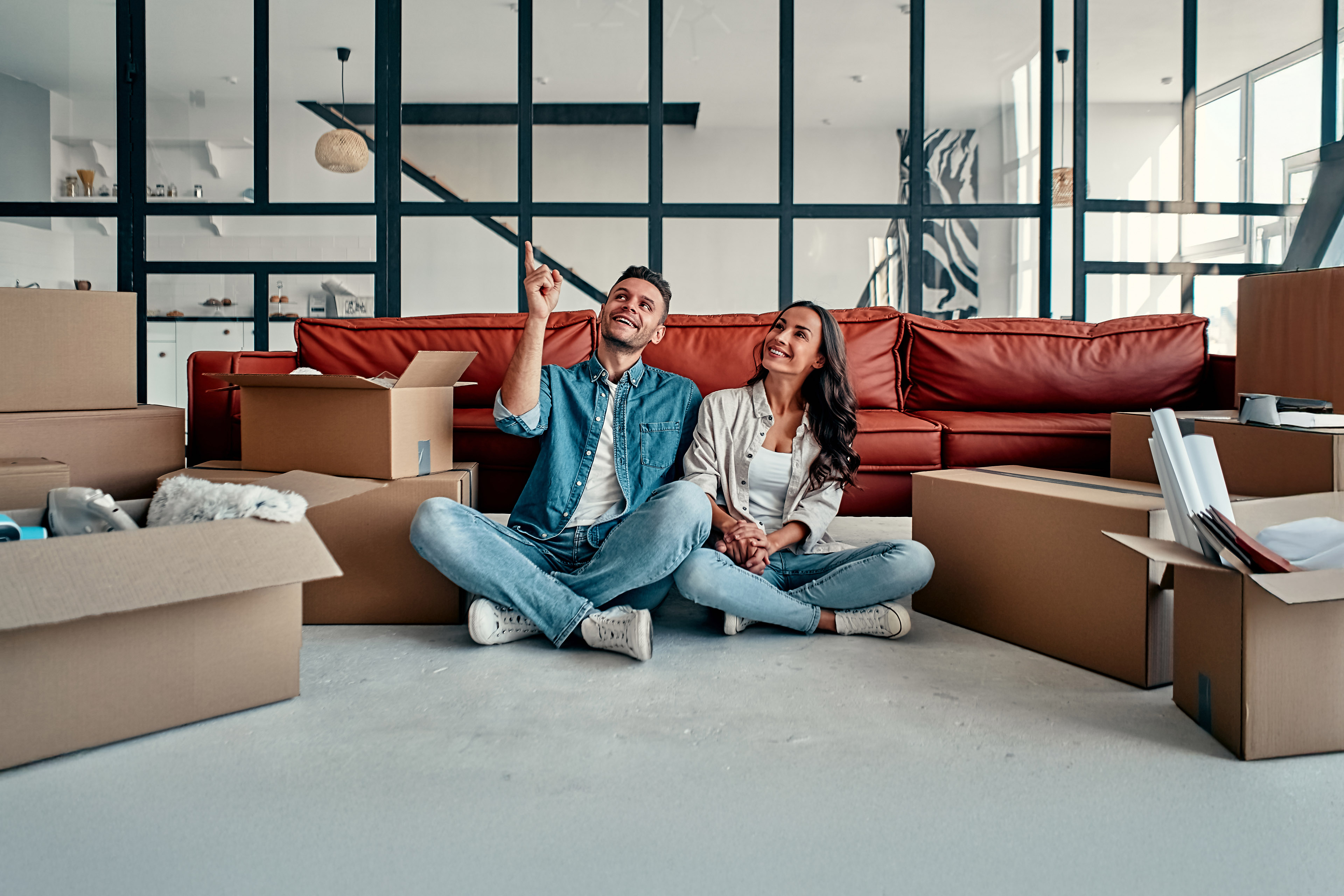 Young married couple sitting on the floor in living room at house.