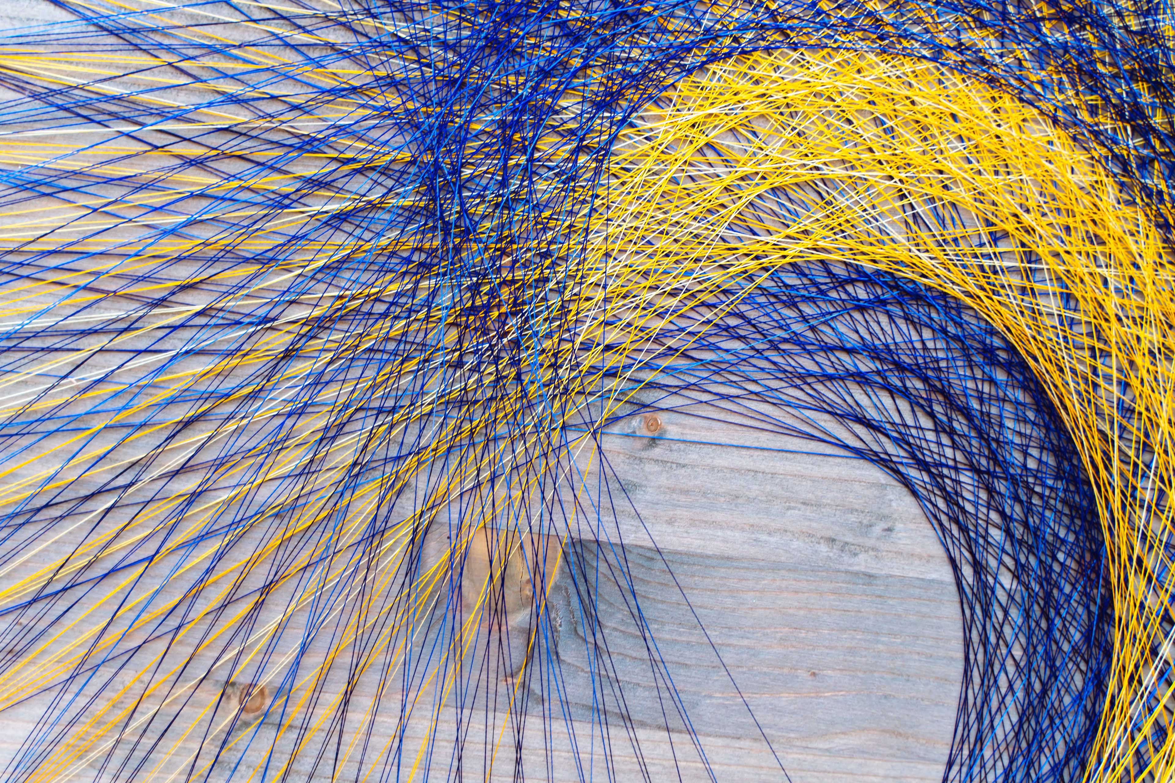 Colored silk thread mandala on a wooden board